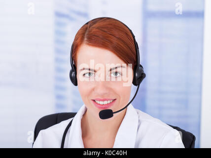Closeup of smiling female customer service representative avec microphone Banque D'Images