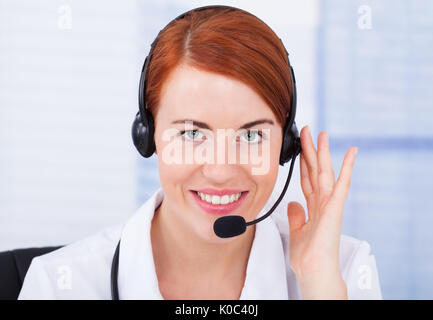 Closeup of smiling female customer service representative avec microphone Banque D'Images