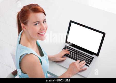 High angle portrait of beautiful young woman using laptop at desk Banque D'Images