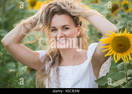 Jeune femme dans un champ de tournesols. coucher du soleil la lumière dans le champ de tournesols Banque D'Images