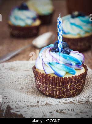 Cupcake fête sur un fond de bois avec des bleuets et crème avec une bougie style rustique. Banque D'Images
