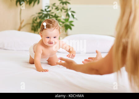 Bébé Enfant joue lentement sur le lit de la mère à l'intérieur Banque D'Images