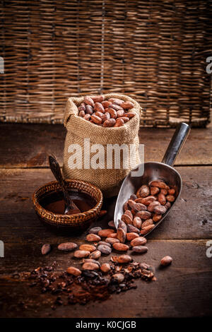 Les fèves de cacao bio en sac de jute et du cacao en poudre dans un bol Banque D'Images