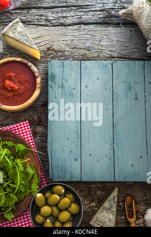 Planches en bois avec de la nourriture. Olives, tomates, basilic et ingrédients sur bois Banque D'Images