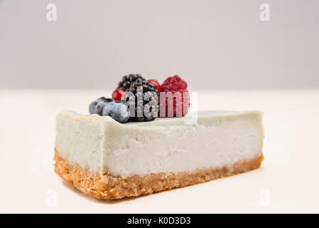 Vue latérale du gâteau au fromage bleu avec différents fruits rouges sur elle isolated over white Banque D'Images