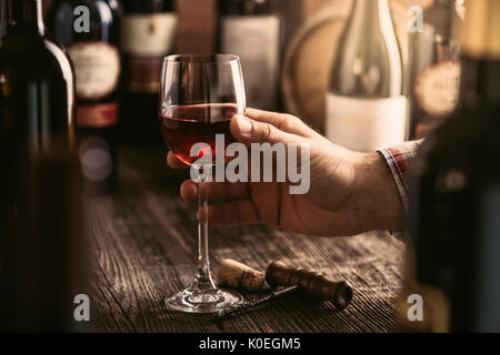 L'expérience de dégustation de vin dans la cave rustique et un bar à vin : sommelier tenant un verre de vin rouge délicieux et d'excellents vins collection sur th Banque D'Images