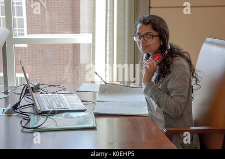 Une étudiante de l'Université Johns Hopkins étudie dans la salle de lecture Brody au Brody Learning Commons avec son ordinateur portable et des ordinateurs portables devant elle avec des écouteurs rouges autour de son cou à l'Université Johns Hopkins, Baltimore, Maryland, 2013. Avec la permission d'Eric Chen. Banque D'Images