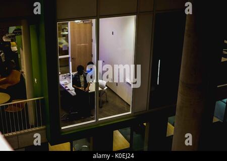 Un cliché de l'ombre de deux étudiants étudiant en chimie organique dans une salle d'étude cubique du Brody Learning Commons de l'Université Johns Hopkins, en train de résoudre des problèmes sur les murs en tableau blanc et en verre, une explication écrite sur le verre; À l'extérieur de la salle, d'autres étudiants s'y posent des problèmes sur les tableaux blancs et les chaises; les tables des étages ci-dessous sont visibles dans l'architecture de l'atrium du bâtiment; Baltimore, Maryland, 2014. Avec la permission d'Eric Chen. Banque D'Images