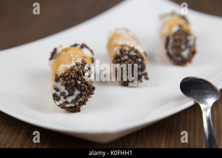 Cannoli siciliens sur blanc plat sur table en bois Banque D'Images