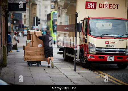 Un camion de livraison pas de parcs et la chaussée double yellow line comme courrier offre des grandes boîtes à la main trolley Banque D'Images