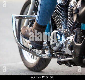 Vue en gros à la femelle les jambes avec des bottes de protection sur les stands de moto du broyeur Banque D'Images