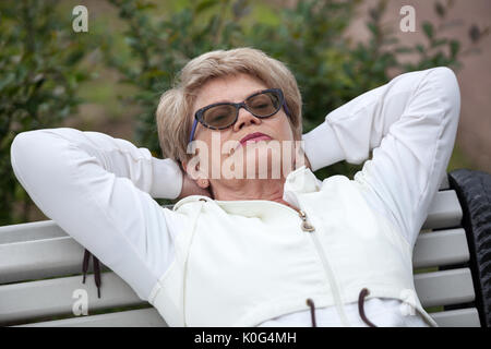 Senior woman in sports fonction pose dos sur le banc de parc après le jogging Banque D'Images