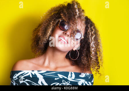 Portrait à l'intérieur d'une femme jeune en lunettes de soleil. Fond jaune. Style de vie. Banque D'Images