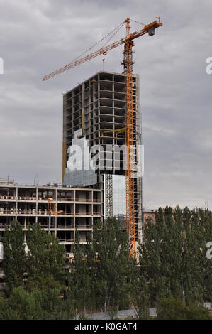 Site de construction d'une grue a tour sur un gratte-ciel spectaculaire contre ciel nuageux. Banque D'Images