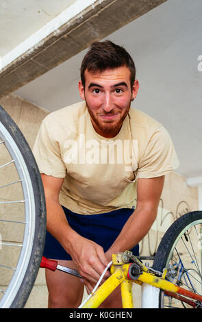 Handsome Man looking at Camera en réparant son Vélo Vintage Banque D'Images