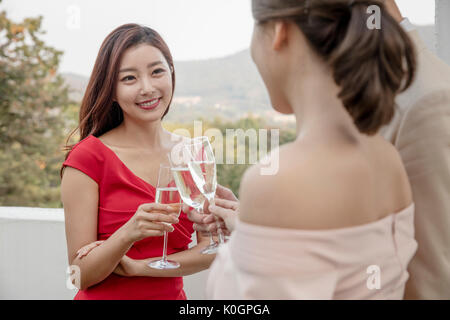 Portrait de jeune femme souriante et ses friends toasting with champagne glasses at party sur le toit Banque D'Images
