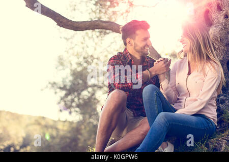 Couple d'amoureux sous un grand arbre dans le parc en automne Banque D'Images