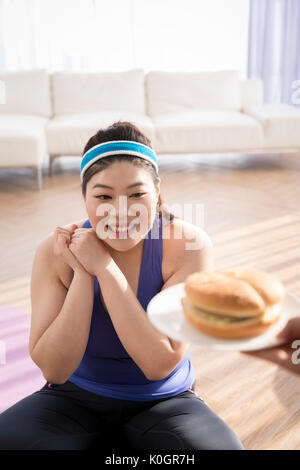 Young smiling woman fat tentés de manger fast-food Banque D'Images