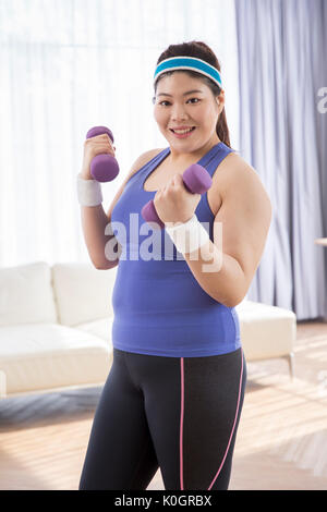 Young smiling woman posing with dumbbells gras Banque D'Images