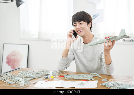 Portrait of smiling male kidult avec maquette avion talking on cellphone Banque D'Images