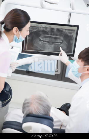 Dentiste et l'hygiéniste dentaire montrant une radiographie à un senior male patient Banque D'Images