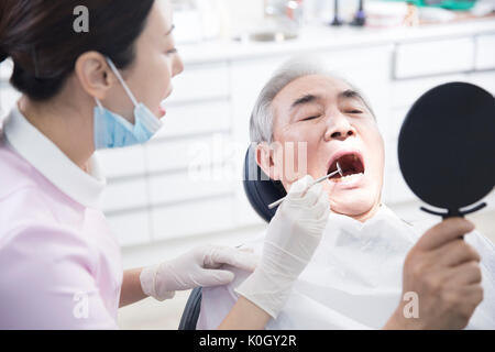 Portrait de l'hygiéniste dentaire curing a senior male patient Banque D'Images