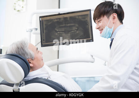 Vue latérale du senior male patient et souriant dentiste Banque D'Images