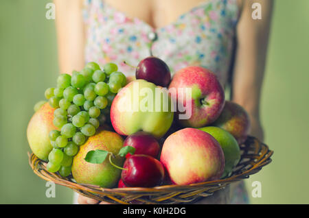 Une grande plaque en bois avec des fruits mûrs dans les mains d'une jeune femme. Concept de récolte Banque D'Images