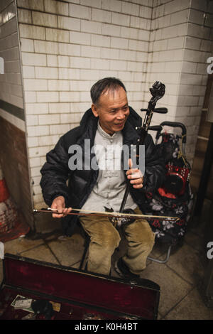 New York, États-Unis d'Amérique - le 9 avril 2017. Un musicien de rue est la lecture de la "Erhu" au milieu de la station de métro. Banque D'Images