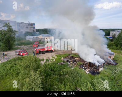 Segezha, Carélie, Russie - circa Jun, 2017 : ouvrir le feu et la fumée dense sont sur granges et maison. Trois personnes lutte avec le feu les pompiers avec ho Banque D'Images