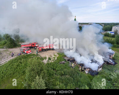 SEGEZHA, Carélie, RUSSIE - CIRCA Jun, 2017 : Normal-pression fire stream déverse sur la combustion de bois des granges. L'équipe de pompiers en vêtements de protection incendie f Banque D'Images