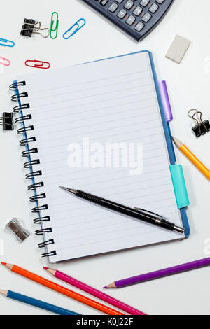 Blank page notes bordée d'un bureau blanc avec une calculatrice et crayons de couleur Banque D'Images