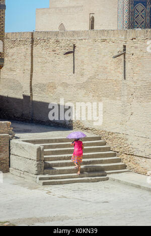 Boukhara, Ouzbékistan - 4 SEPTEMBRE : Woman in dress marche sur l'escalier derrière la mosquée Kalyan sur une chaude journée d'été. Septembre 2016 Banque D'Images