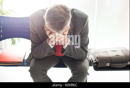 Desperate businessman dans la salle d'attente avec la tête dans les mains, il est en attente d'une entrevue d'emploi, le chômage et l'échec de l'entreprise concept Banque D'Images