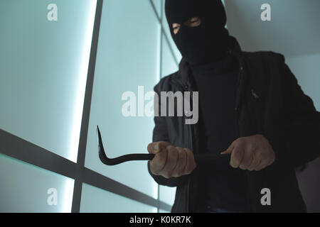 Cambrioleur dangereux avec un pied de biche pour pénétrer dans une chambre tard dans la nuit, le concept de sécurité accueil Banque D'Images