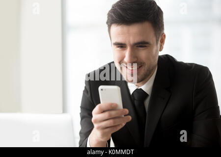 Smiling businessman looking at smartphone en main, à l'aide de mobile Banque D'Images