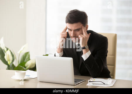 Businessman frustré souffrant de maux de tête Migraine à workp Banque D'Images