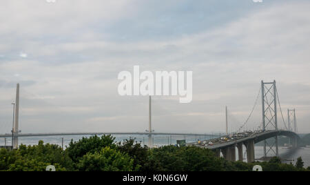 South Queensferry, Ecosse, Royaume-Uni. Vue de South Queensferry du nouveau franchissement Queensferry tel qu'il est presque terminé avec l'heure de pointe sur le Forth Road Bridge Banque D'Images