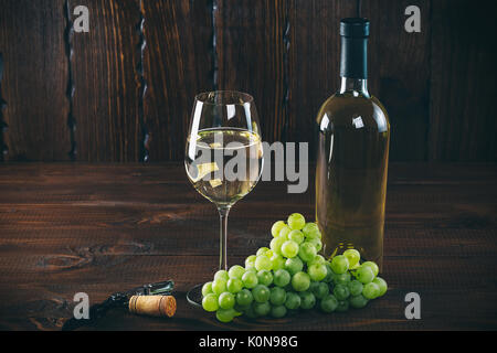 Beau vin blanc dans un verre de vin avec un tas de raisins verts, sur un fond de bois avec de l'espace libre Banque D'Images