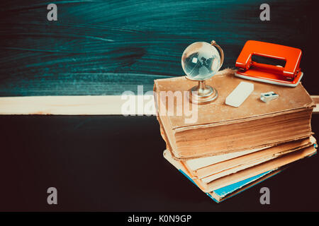 Vieux tableau noir avec des craies, des livres, un globe et un crayon. Une belle toile de fond pour l'éducation, un espace libre pour votre texte. retour à l'école. shallow dof. Banque D'Images