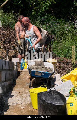 Les travailleurs qui construisent un mur de bloc sur un chantier de construction. Banque D'Images