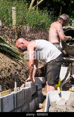 Les travailleurs qui construisent un mur de bloc sur un chantier de construction. Banque D'Images