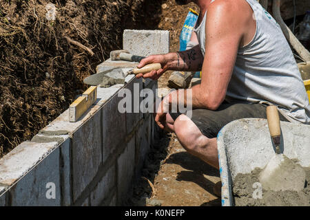 Les travailleurs qui construisent un mur de bloc sur un chantier de construction. Banque D'Images