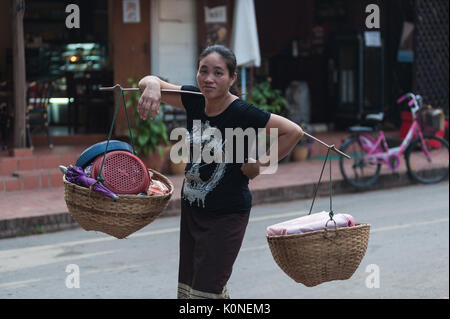 Femme porte Lao marchandises dans des paniers accrochés sur une palanche au marché local, Luang Prabang, Laos. Banque D'Images