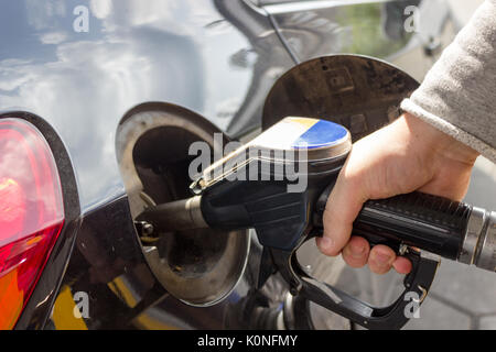 Close-up of hand refueling car le réservoir de la pompe à essence en maintenant la buse. Banque D'Images