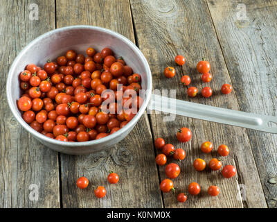 Les tomates cerise lavées dans une passoire metall sur ancienne en bois table patiné Banque D'Images