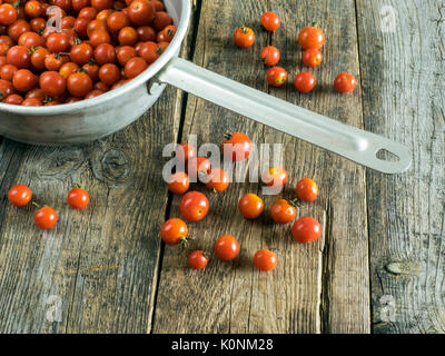 Les tomates cerise lavées dans une passoire metall sur ancienne en bois table patiné Banque D'Images