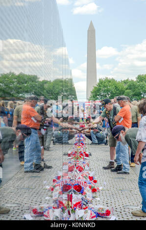 Les visiteurs regarder les noms et les objets laissés à la Vietnam Veterans Memorial wall à Washington DC. Banque D'Images