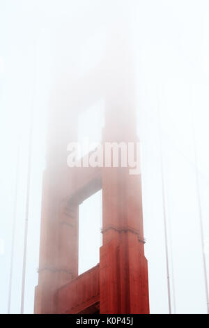 Tour rouge de style Art déco du Golden Gate Bridge qui s'élève et disparaît dans le brouillard Banque D'Images