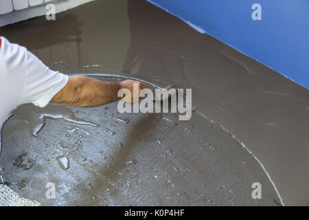 Worker met une chape d'auto-nivellement sur plancher de béton en chambre Banque D'Images